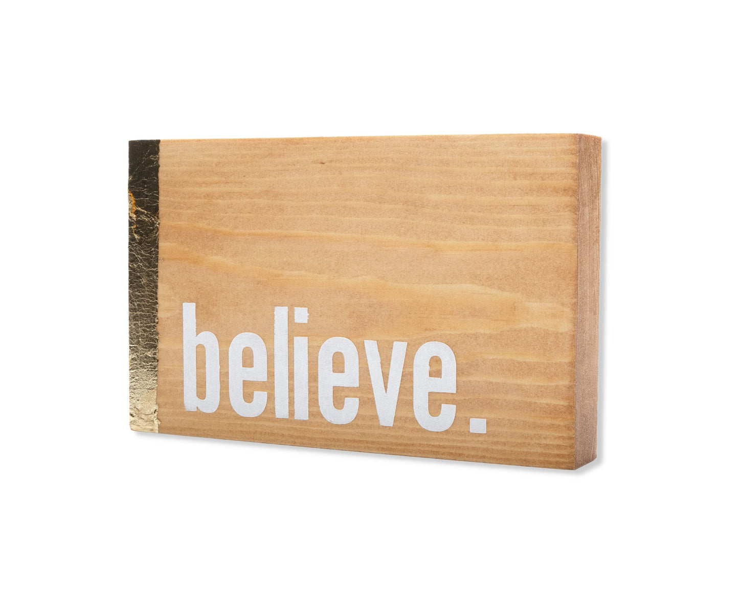 Small freestanding rectangular wooden sign displayed at 35 degree angle to show depth of sign. Natural wood color, with gold vertical border on left side only. White painted message in chunky font and full stop, believe. Studio style photo.
