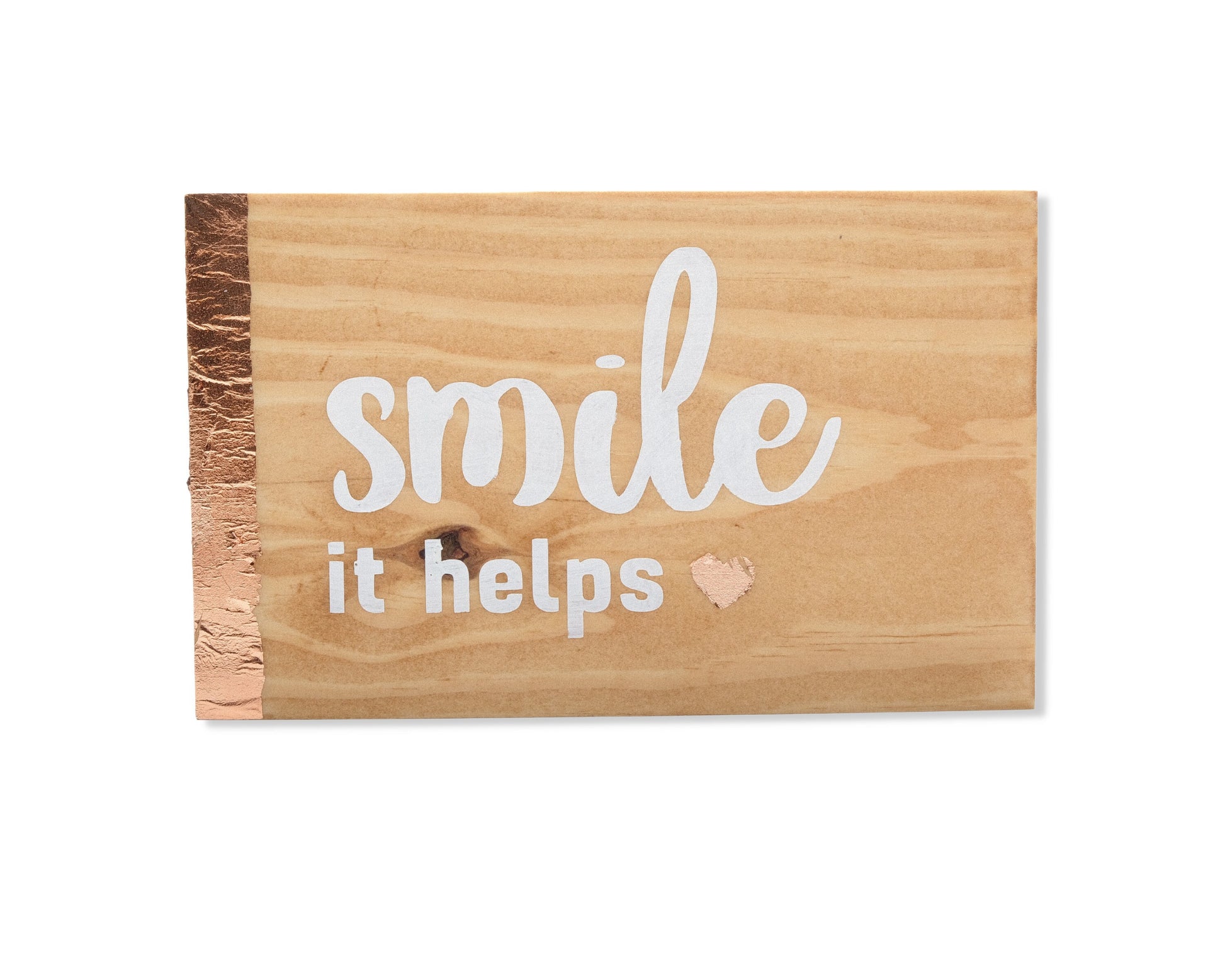 Small freestanding rectangular wooden sign facing straight on. Natural wood color, bronze rose gold vertical border on left side. White painted message, smile it helps. Small solid heart in bronze rose gold. Studio style photo with white background.