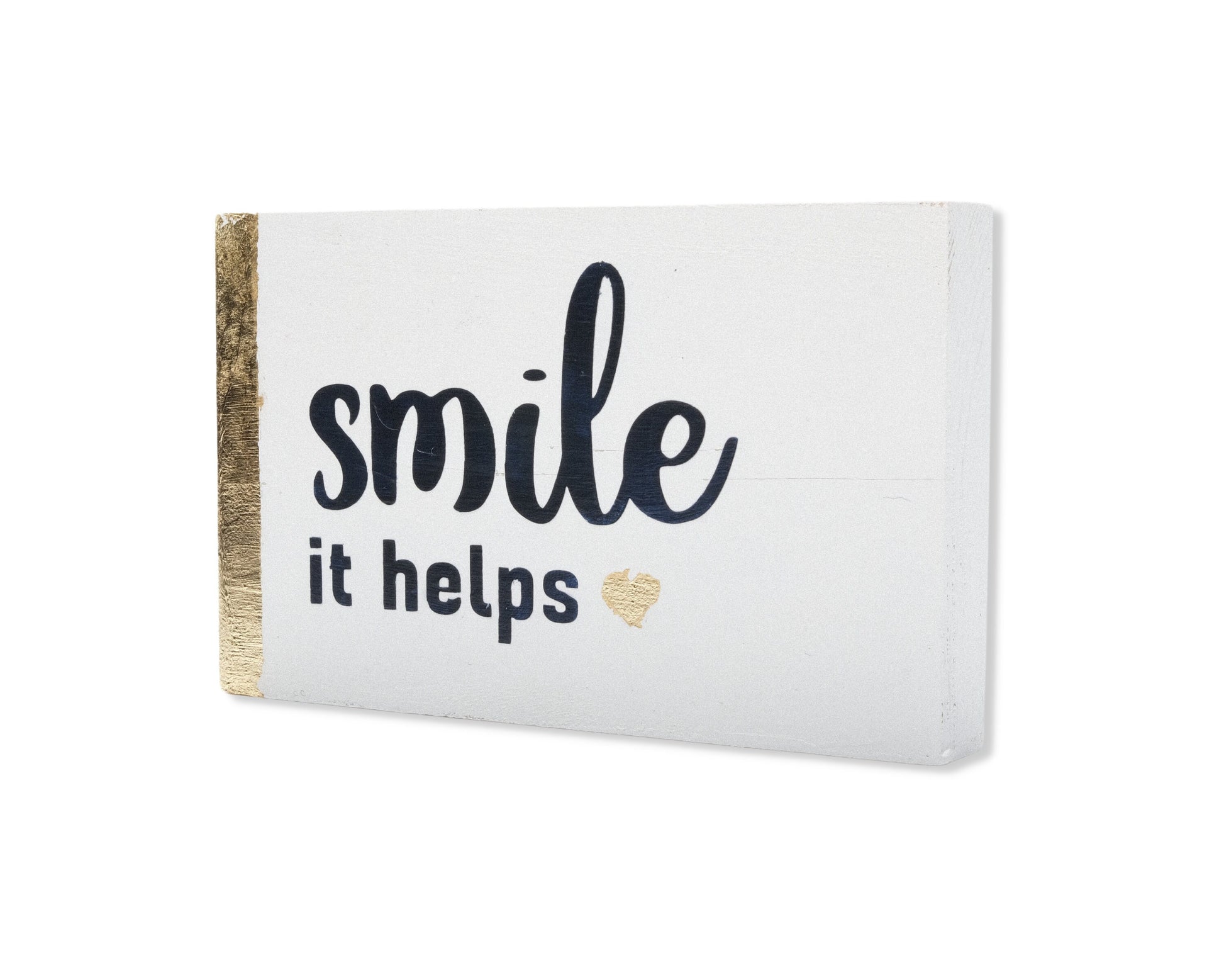 Small freestanding rectangular wooden sign displayed at 35 degree angle to show depth of sign. White wood stain, with gold vertical border on left side only. Black painted message, Smile it helps. Small solid heart in gold. Studio style photo.